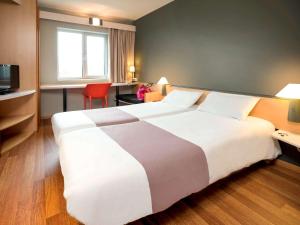 沙勒罗瓦沙勒罗瓦中心火车站宜必思酒店的酒店客房设有一张白色大床和一个窗户。