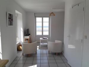 杜瓦讷内LE STUDIO DU RIS的客厅配有两把白色椅子和窗户