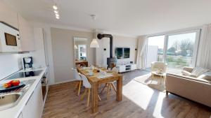 格洛米茨Beach'n'Sea Wohnung 7的厨房以及带木桌和椅子的客厅。