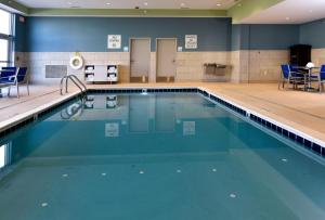 麦迪逊维尔Holiday Inn Express & Suites - Madisonville, an IHG Hotel的一个带蓝色椅子的健身房内的游泳池