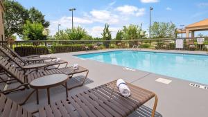 罗阿诺克拉皮兹SureStay Plus Hotel by Best Western Roanoke Rapids I-95的一个带椅子和桌子的游泳池以及一张桌子