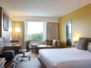 奥克兰奥克兰艾勒斯利诺富特酒店的酒店客房设有一张大床和一张书桌。
