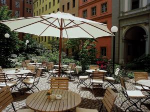 柏林美居酒店柏灵查勒边检站店的一个带桌椅和遮阳伞的庭院