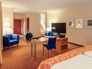 柏林美居酒店柏灵查勒边检站店的酒店客房配有一张床和一张书桌及一台电视