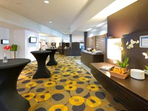 鲁汶诺富特勒芬中心酒店的酒店大堂设有黄色和黑色的地毯