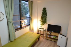 别府Comfort CUBE PHOENIX Beppu (やよいビル)的客厅配有绿色沙发和电视