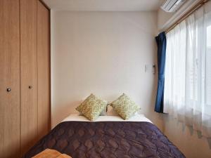 北谷町M´s Stay Okinawa的一间卧室配有带两个枕头的床和窗户