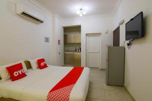 塞拉莱Qumra Furnished Apartments的一间卧室配有一张带红色枕头的床和一台平面电视。