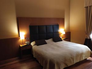 巴勒莫博塔菲里斯酒店及水疗中心的一间卧室配有一张带两盏灯的大型白色床。