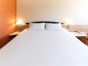 穆尔西亚宜必思穆尔西亚酒店的一张大白床,位于带两盏灯的房间