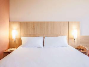 里波列特宜必思里波列特酒店的一张带白色床单和两个枕头的大床
