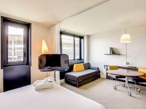 圣但尼巴黎法兰西体育场诺富特套房酒店的酒店客房配有床、沙发和电视。