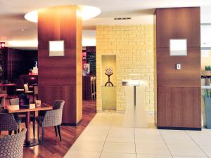 托伦托伦中心美居酒店的餐厅设有桌椅和墙上的时钟