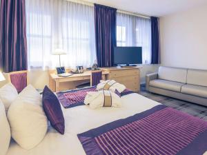 图尔美居旅游中心会议中心酒店的酒店客房设有一张大床和一张沙发。