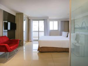 巴西利亚巴西利亚利德美居酒店的酒店客房,配有一张床和一张红色椅子