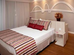 巴西利亚巴西利亚利德美居酒店的卧室配有带红色枕头的大型白色床