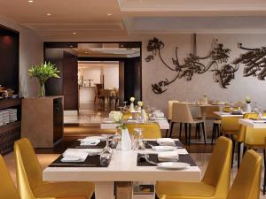 麦加普尔曼赞姆赞姆麦加酒店的餐厅设有白色的桌子和黄色的椅子