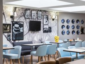 尼斯Ibis Styles Nice Centre Port的一间带桌椅的餐厅以及墙上的电视