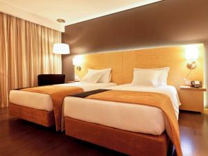 布拉加布拉加市区美居酒店的酒店客房,配有两张床和椅子