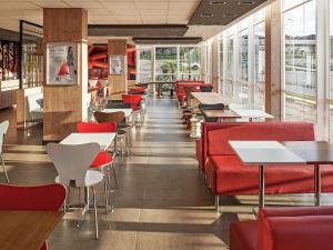 隆德里纳隆德里纳宜必思酒店的餐厅设有红色的椅子和桌子以及窗户。
