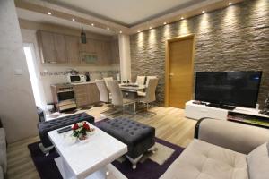 巴伊纳巴什塔Relax Apartment的一间带大电视和厨房的客厅