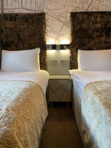 格拉斯哥Babbity Bowsters的一间设有两张床和一堵带绘画的墙壁的房间