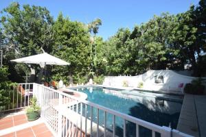 洛杉矶贝弗利山名人之家别墅的一个带白色围栏和遮阳伞的游泳池