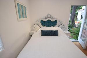 洛杉矶贝弗利山名人之家别墅的一张白色的床,上面有蓝色的枕头