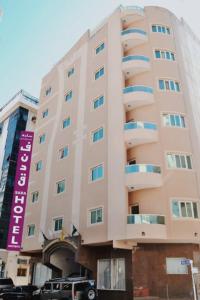 阿吉曼Sara Hotel Apartments的一座大建筑,旁边有一个紫色标志