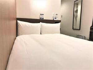 水户欢笑美图酒店的一张白色大床,配有白色床单和枕头