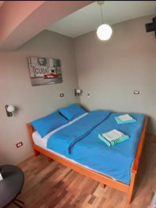 地拉那Elisabet Tirana的一间卧室配有一张带蓝色床单和蓝色枕头的床。