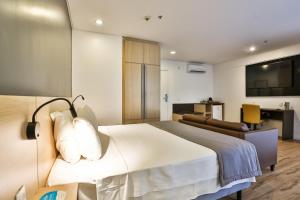 马瑙斯马瑙斯品质酒店的一间卧室配有一张床、一张沙发和一台电视