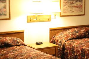 WibauxRodeway Inn Gateway to Medora T-Roosevelt & Makoshika State Park的酒店客房设有两张床和一张桌子上的电话