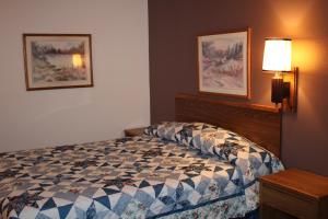WibauxRodeway Inn Gateway to Medora T-Roosevelt & Makoshika State Park的一间卧室配有一张床、一张桌子和一盏灯