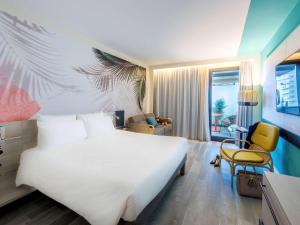 蒙特卡罗蒙特卡罗诺富特酒店的卧室配有一张白色大床和一把椅子