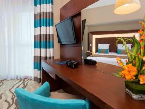 迪拜迪拜阿尔巴沙诺富特酒店的酒店客房配有一张床和一张书桌及一台电视