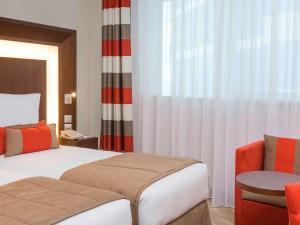 迪拜迪拜阿尔巴沙诺富特酒店的配有一张床和一把椅子的酒店客房