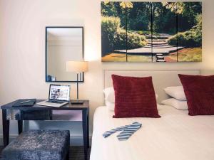 多尔金伯福德桥博克斯希尔美居酒店的一间卧室配有一张带书桌和镜子的床