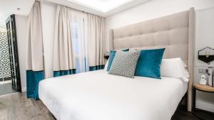 马德里里贾纳酒店的卧室配有带蓝色枕头的大型白色床