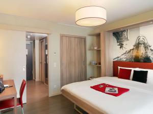 慕尼黑慕尼黑市阿德吉奥公寓式酒店的一间卧室配有一张床和一张带红色毯子的书桌