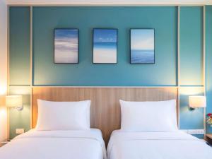 芭东海滩Ibis Phuket Patong的墙上有三张照片的房间的两张床