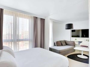 伊西莱穆利诺伊斯莱斯利诺巴黎诺富特套房酒店的白色的酒店客房 - 带一张床和一张沙发