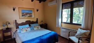 坎德莱达卡米诺乡村酒店的一间卧室配有一张带蓝色床单的床和两个窗户。