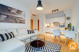 米兹多洛杰Apartamenty Aquamarina - visitopl的一间带白色沙发的客厅和一间厨房
