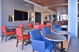 奥拉西Holiday Inn Express & Suites - Olathe West, an IHG Hotel的餐厅设有桌椅和平面电视。