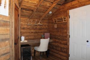 西黄石Elkhorn Cabins and Inn的木墙内的房间,配有白色椅子