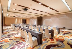 无锡无锡太湖皇冠假日酒店的一间会议室,配有长桌子和白色椅子