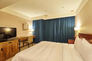 中和全家旅店 的酒店客房配有一张床、一张书桌和一台电视。