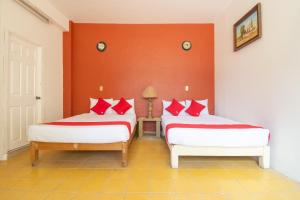 萨卡特卡斯OYO Hotel Meson de la Concepcion的红色墙壁客房的两张床