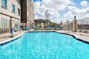 圆石城Holiday Inn Express & Suites Round Rock Austin North, an IHG Hotel的一座带蓝色椅子的游泳池和一座建筑